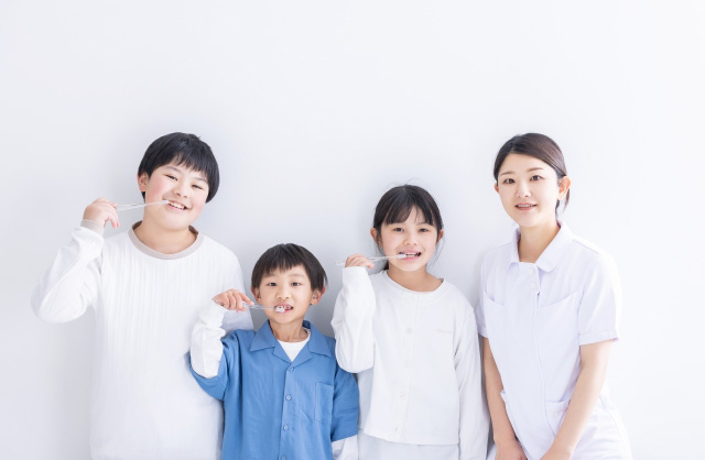 歯みがきをする3人の子供と歯科衛生士